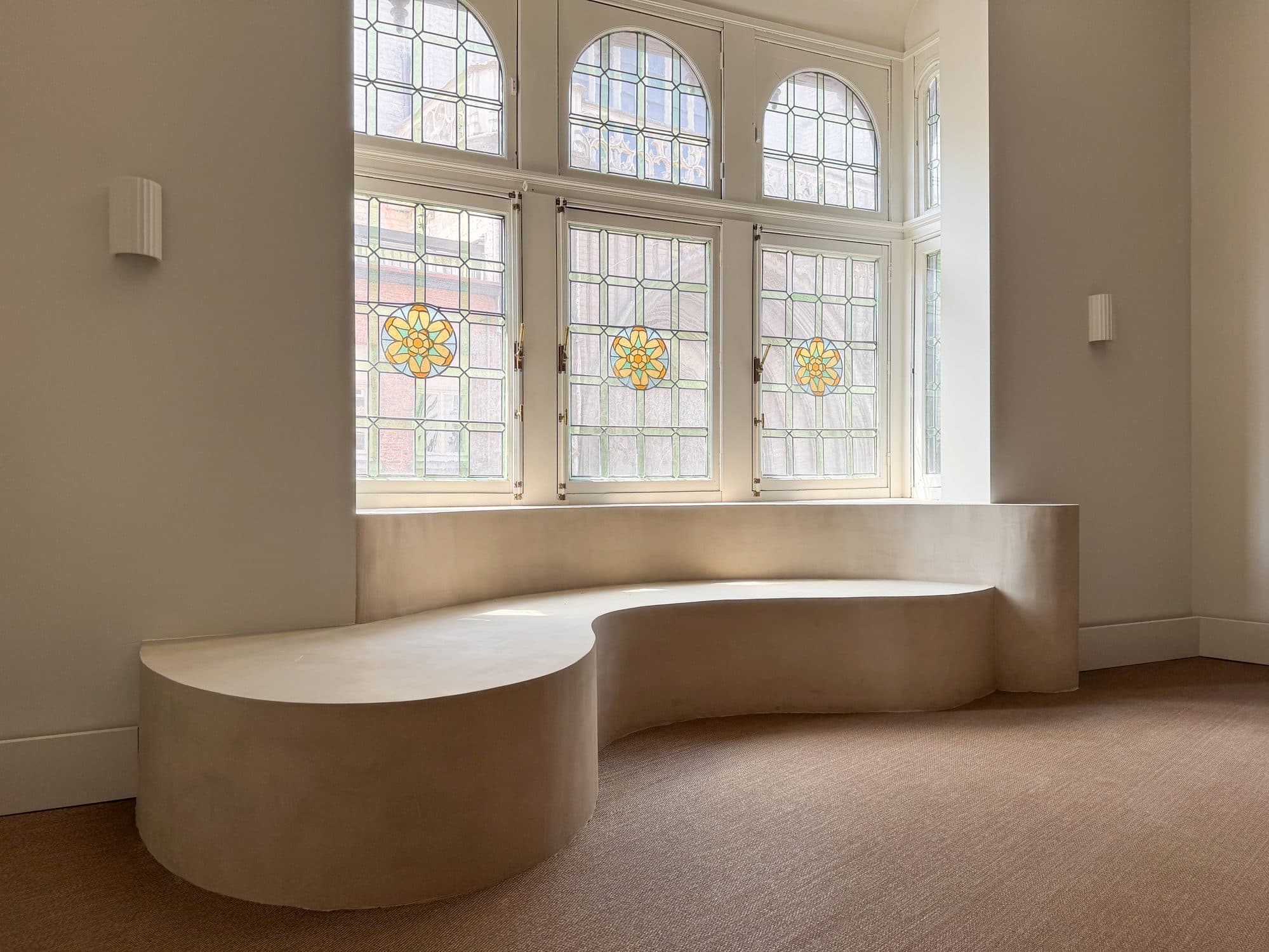 Gebogen bank onder de loodglasramen